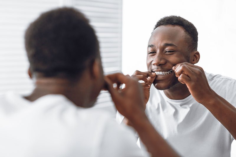 Smiling man using dental floss