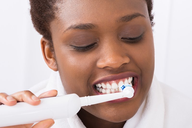 Close-up Of A Young Woman Brushing Teeth With Electric Brush